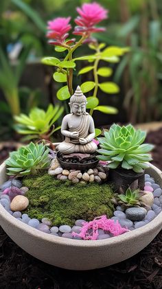 a buddha statue sitting on top of a bowl filled with rocks and succulents