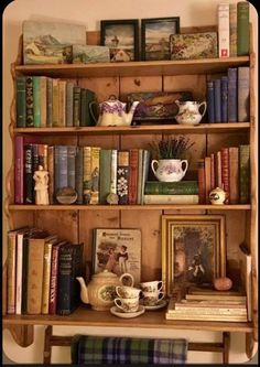 an old book shelf with books and tea cups on it