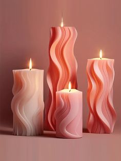 three candles that are sitting next to each other on a pink surface with one candle lit