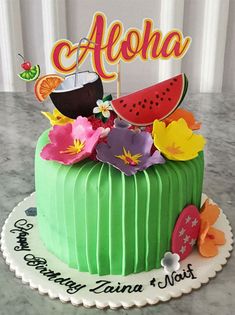 there is a green cake with watermelon and flowers on the top that says aloha