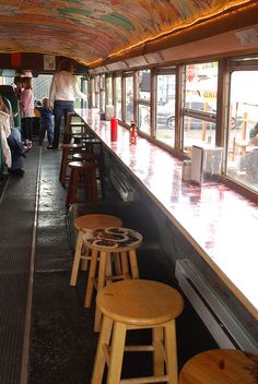 people are lined up in the back of a bus with wooden stools and tables