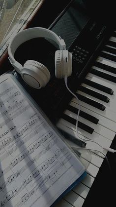 an open book with headphones sitting on top of it next to a piano keyboard