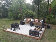 an outdoor seating area made out of wood and gravel with fire pit in the middle