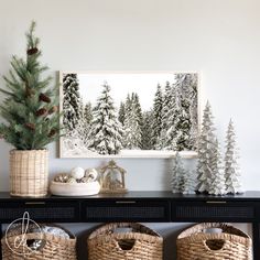 christmas trees and baskets sit on a table in front of a wall with a painting