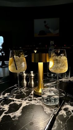 three glasses filled with yellow liquid sitting on top of a marble counter next to each other