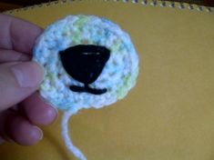 a crocheted sheep brooch with a black nose