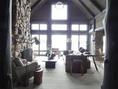 a living room filled with lots of furniture next to a stone wall covered in windows