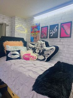 a bedroom with white brick walls, black and pink pillows and pictures on the wall