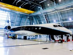 an airplane is parked in a large hanger with people standing around and looking at it