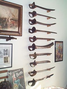 there are many old knives hanging on the wall next to pictures and framed photos in this room