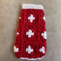 a red and white crocheted cell phone case sitting on top of a table