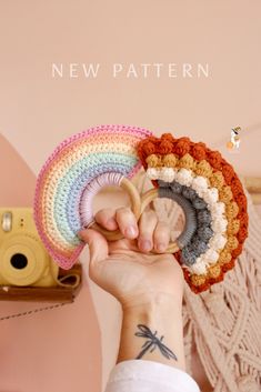 a person holding up a crocheted rainbow hat