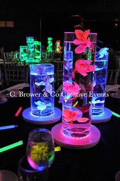 several vases with flowers in them are lit up