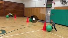 two young boys are playing with balls in an indoor gym