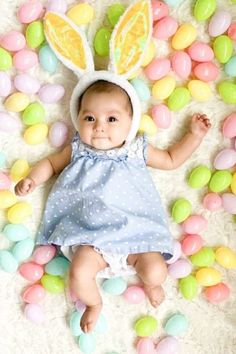 a baby wearing an easter bunny costume laying on some colored eggs