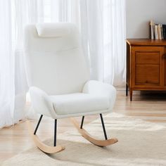 a white rocking chair sitting on top of a rug in front of a wooden dresser