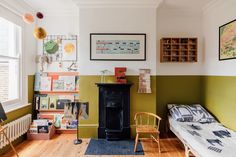 a bedroom with green walls and wooden floors, a fireplace in the corner and pictures on the wall