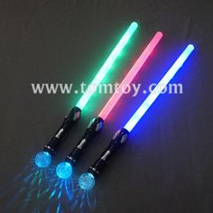 three different colored lightsabes on a black surface with white and blue lightening