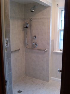 a walk in shower sitting next to a window on top of a white tiled floor