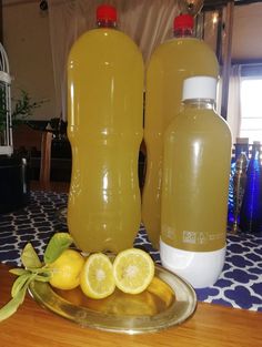 two large jugs of lemonade sit on a table next to some sliced lemons