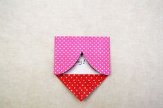 an origami cat in a pink and red polka dot pocket