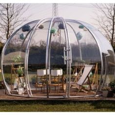 a large round glass structure sitting on top of a lush green field