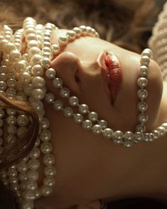 a woman with pearls on her head and necklaces around her neck is laying down