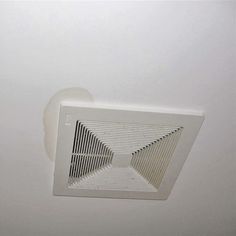 a bathroom exhaust fan mounted to the ceiling above a toilet paper dispenser