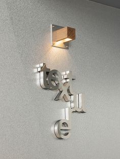 a wall light mounted on the side of a white wall next to a wooden sign