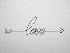 the word love with an arrow drawn in black ink on a white background, made from wire