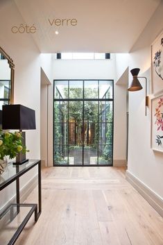 a hallway with glass doors and wooden flooring next to a wall mounted planter