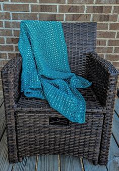 a blue blanket sitting on top of a wicker chair next to a brick wall