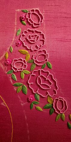 pink fabric with flowers and green leaves on the side, along with thread in between