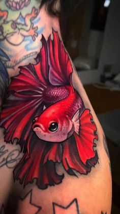 a man with a tattoo on his chest has a red fish in the middle of his arm