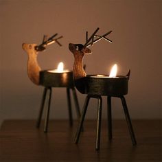 two deer candles sitting on top of a table next to each other with one candle in the middle