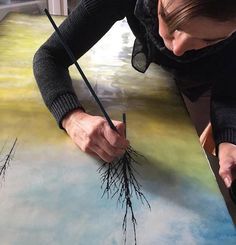 a woman is painting with water and trees