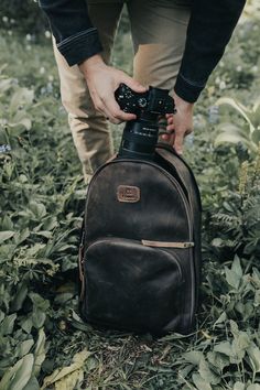 a man is holding a camera in his backpack