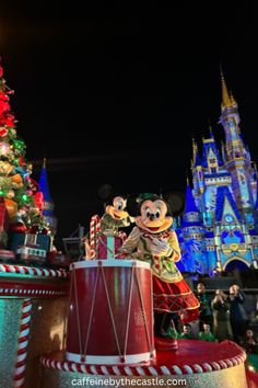 mickey and minnie mouse in front of the christmas tree at disney world's magic kingdom