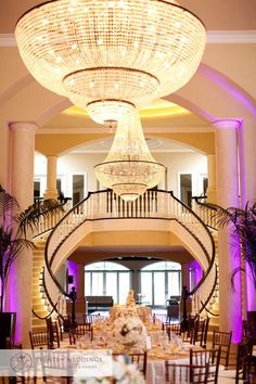 a large chandelier hangs from the ceiling above a dining room table set for a formal function