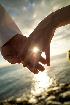 two people holding hands with the sun behind them