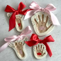 three ceramic handprints with red bows on them and two hands in the middle