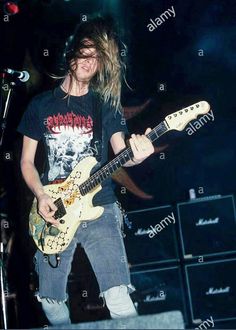 a man with long hair playing an electric guitar on stage