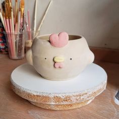 there is a cake shaped like a cat on top of a table with pens and pencils in the background