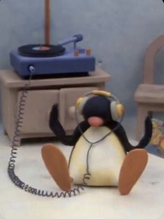 a toy penguin with headphones sitting in front of a record player