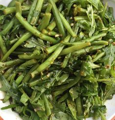 a white bowl filled with green vegetables on top of a table