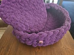 a purple crocheted basket sitting on top of a wooden table