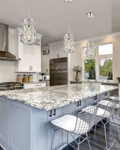 a large kitchen with marble counter tops and stainless steel appliances, along with two bar stools