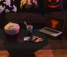 a table with a laptop, drink and halloween pillows on it next to a cup of coffee