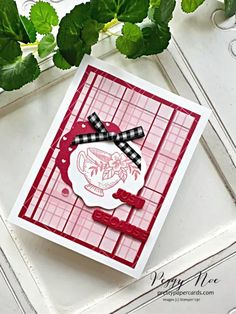 a close up of a card on a table with green leaves and flowers in the background