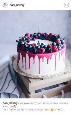 a cake with berries, blueberries and raspberries is on a wooden stand